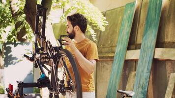 caucasien Masculin cycliste raccommodage le sien posséder vélo dans le Cour Faire annuel Extérieur véhicule entretien en utilisant professionnel équipement. examiner et réparer bicyclette équipement comme été passe-temps. photo