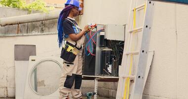 efficace mécanicien à la recherche à réfrigérant les niveaux dans externe air Conditionneur tandis que en utilisant collecteur indicateurs à méticuleusement mesure le pression dans HVAC système, assurer efficace refroidissement performance photo