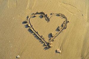 une image de une cœur sculpté dans le plage le sable lequel symbolise l'amour photo