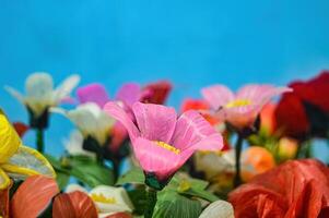 Plastique fleur bouquets pour décoration sur une plaine bleu mur Contexte photo