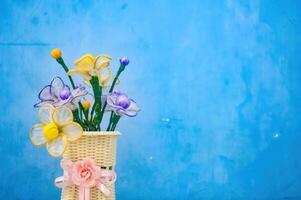 une bouquet de Plastique fleurs dans une fleur pot lié avec une rose ruban dans le forme de une fleur photo