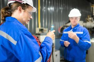 ingénieurs et techniciens travail ensemble dans une robotique bras usine, vérifier le Puissance transmission lignes de le robotique bras. photo