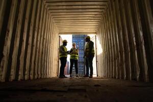 groupe de ouvriers dans un vide récipient espace de rangement cour, le état de le vieux récipient est étant évalué à déterminer qu'il s'agisse il a besoin entretien pour usage. photo