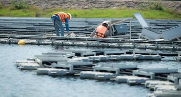 tous les deux de techniciens sont actuellement évaluer et réparer le transmission terminaux pour électricité généré par solaire énergie dans une flottant solaire Puissance système. photo