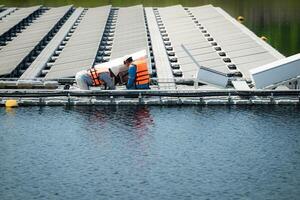 tous les deux de techniciens sont actuellement évaluer et réparer le transmission terminaux pour électricité généré par solaire énergie dans une flottant solaire Puissance système. photo