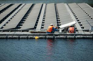 tous les deux de techniciens sont actuellement évaluer et réparer le transmission terminaux pour électricité généré par solaire énergie dans une flottant solaire Puissance système. photo