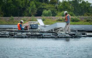 tous les deux de techniciens sont actuellement évaluer et réparer le transmission terminaux pour électricité généré par solaire énergie dans une flottant solaire Puissance système. photo