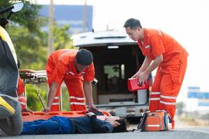 le paramédical est assistant un blessé homme dans un urgence situation sur le route. photo