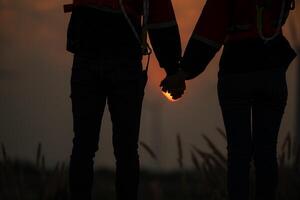 silhouette de une homme et femme en portant mains sur le coucher du soleil Contexte photo