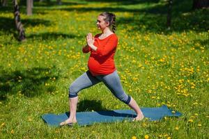 Enceinte femme Faire asana virabhadrasana en plein air photo