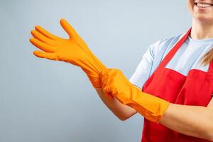 une femme dans rouge tablier en mettant sur protecteur gants sur bleu Contexte photo