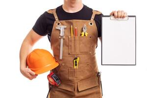 Masculin ouvrier ou constructeur dans tablier avec casque en portant une presse-papiers photo