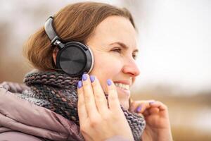 joyeux Jeune femme dans veste écoute à musique, relaxant dans une parc photo