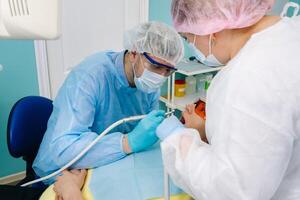 une femelle patient dans dentaire des lunettes traite les dents à le dentiste avec ultra-violet lumière. dentaire plombages photo