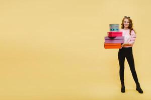 une content Jeune femme avec coloré papier des boites après achats isolé sur un Orange studio Contexte. saisonnier ventes, achats, dépenses argent sur cadeaux photo