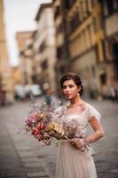 le fille-mariée est avec magnifique fleur modèle comme une masque dans Florence, élégant la mariée dans une mariage robe permanent avec une masque dans le vieux ville de Florence. modèle fille dans Florence photo