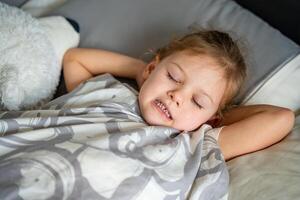 mignonne peu fille en train de dormir et broyage les dents dans rêves, serré les dents avec fatigue et stress. haute qualité photo