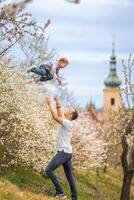 père et fille ayant une amusement ensemble en dessous de une épanouissement arbre dans printemps parc pétrin dans Prague, L'Europe  photo