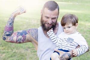 tatoué père avoir amusement avec le sien fils dans le parc photo