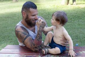 tatoué père avoir amusement avec le sien fils dans le parc photo