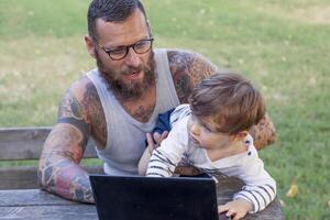 tatoué papa avoir amusement avec le sien fils et portable photo