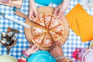 groupe de copains en mangeant Pizza. Haut vue de quatre mains prise Pizza tranches photo