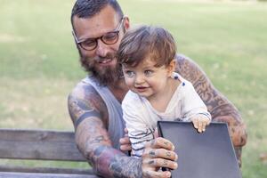 tatoué papa avoir amusement avec le sien fils et portable photo
