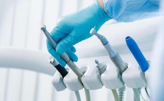 une dentiste portant gants dans le dentaire Bureau détient une outil avant travail photo