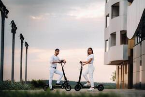 une fille et une gars sont en marchant sur électrique scooters autour le ville, une couple dans l'amour sur scooters. photo