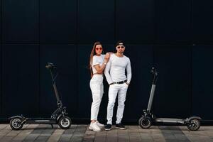 une fille et une gars sont en marchant sur électrique scooters autour le ville, une couple dans l'amour sur scooters. photo