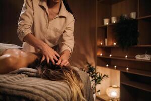 une masseuse donne une tête massage à une femme à le spa. une professionnel masseur massages le tête de une fille mensonge dans une spa centre photo