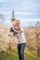 père et fille ayant une amusement ensemble en dessous de une épanouissement arbre dans printemps parc pétrin dans Prague, L'Europe  photo