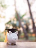 porcin banque avec l'obtention du diplôme chapeau. le concept de économie argent pour éducation, étudiant prêt, bourse, frais de scolarité honoraires dans futur photo