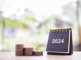 2024 bureau calendrier et empiler de pièces de monnaie. le concept de affaires croissance, financier investissement, marché action, profit retour, dividende et affaires fonds dans année 2024 photo