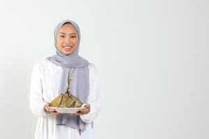 indonésien femelle en portant blanc assiette avec riz gâteau avec diamant forme pour musulman de fête photo