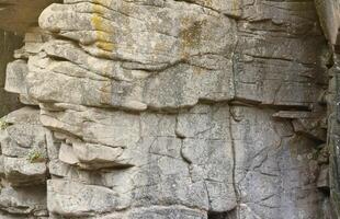 fond de pierre de roche naturelle grossière légère. surface avant rugueuse de la falaise minière. toile de fond de grande pile de calcaire. grunge lourd texture de bloc de granit endommagé photo