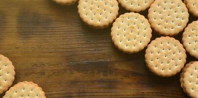 un biscuit sandwich rond fourré à la noix de coco se trouve en grande quantité sur une surface en bois marron. photo de friandises comestibles sur un fond en bois avec espace de copie