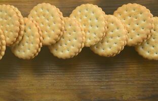 un biscuit sandwich rond fourré à la noix de coco se trouve en grande quantité sur une surface en bois marron. photo de friandises comestibles sur un fond en bois avec espace de copie