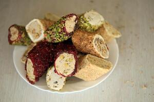 beaucoup Rouleaux de turc délice avec différent les saveurs et plombages dans blanc assiette sur tableau. coupes de Turc lokumu photo