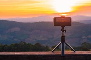 une téléphone intelligent est enregistrement le Soleil réglage plus de une Montagne gamme. photo