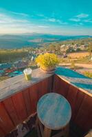 une vue de le colline de le café boutique, comprenant une le coucher du soleil dans le Contexte et une en bois chaise mis dans une coin. photo