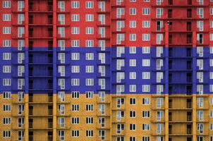 Arménie drapeau représenté dans peindre couleurs sur à plusieurs étages résidentielle bâtiment en dessous de construction. texturé bannière sur brique mur Contexte photo