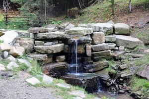 proche en haut de une petit cascade effusion plus de mousse couvert rochers dans régional parc. Fait main rivière cascade photo