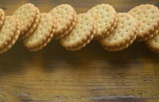 un biscuit sandwich rond fourré à la noix de coco se trouve en grande quantité sur une surface en bois marron. photo de friandises comestibles sur un fond en bois avec espace de copie