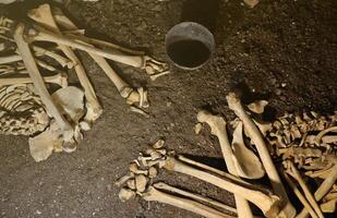 crâne et des os creusé de fosse dans le effrayant cimetière de les prisonniers photo