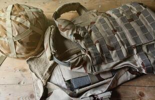 une militaire casque de une ukrainien soldat avec une lourd blindé gilet sur en bois table dans point de contrôle pirogue photo