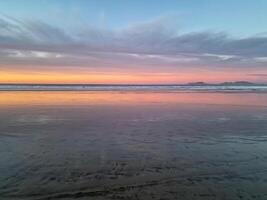 le coucher du soleil à playa de famara, lanzarote, des peintures le ciel avec vibrant teintes, moulage une fascinant lueur plus de le horizon. Stupéfiant vue cette capture le essence de tranquillité et Naturel beauté. photo