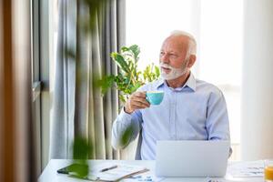 coup de une Sénior financier homme d'affaire séance dans le sien Bureau et en buvant une tasse de café tandis que prise une Pause. photo