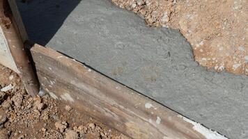 construction Contexte par ciment. ciment est versé sur le sol et là sont en bois planches à limite le limites de le fondation placement. photo