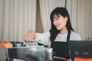 une souriant barista dans une noir tablier arrange tasses à une café boutique, sa agréable comportement ajouter chaleur à le ambiance. photo